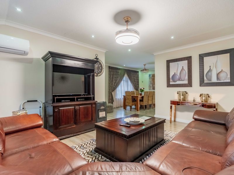 Spacious open-plan living and dining area featuring neutral walls, laminate flooring, recessed lighting, and a wall-mounted air conditioning unit.