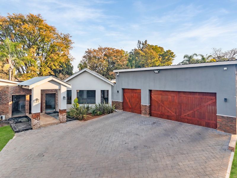 Front elevation of a modern house featuring a spacious paved driveway, double timber garage doors, and a covered entrance porch.
