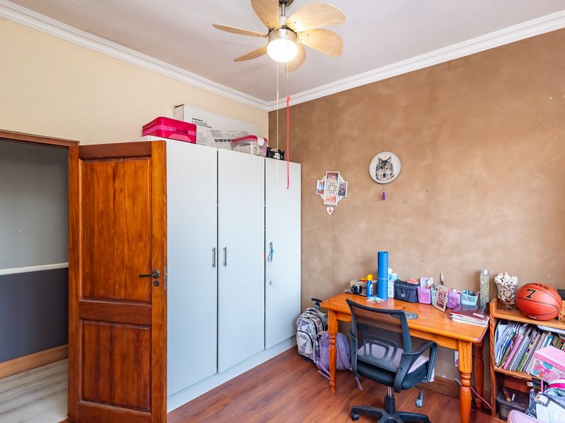 A bedroom featuring laminate flooring, a ceiling fan, and a built-in wardrobe with white cabinetry.