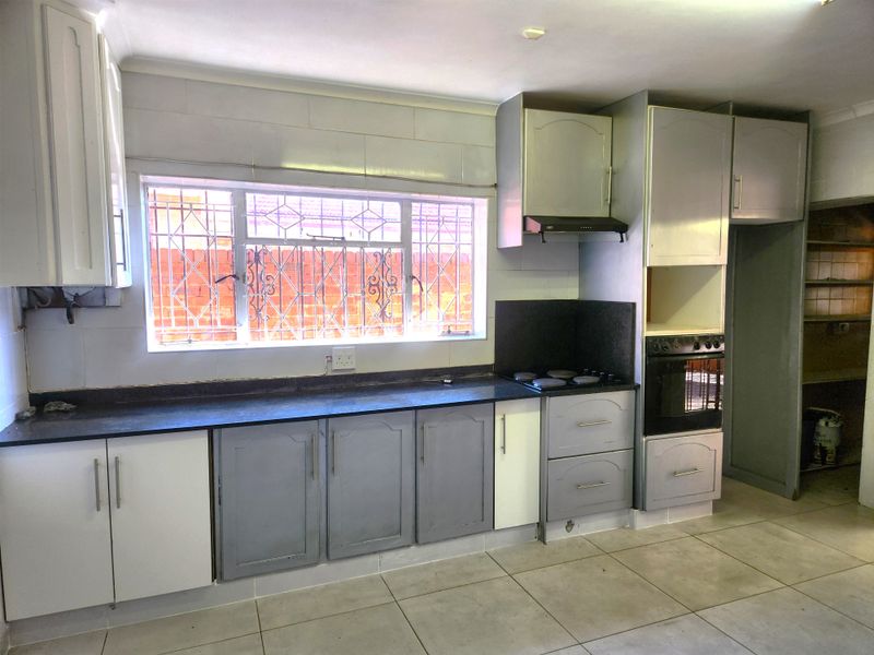 A functional kitchen featuring built-in cabinetry, an integrated oven and hob, tiled splashbacks, and tiled flooring, offering a blank canvas for renovation.