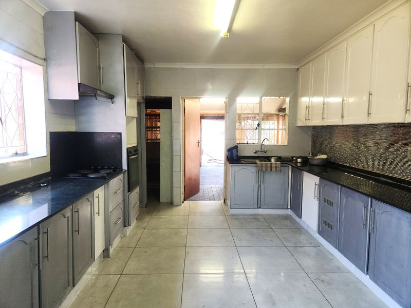 A functional kitchen featuring granite countertops, built-in cabinetry, an electric hob, and an oven, with direct access to an outdoor area.