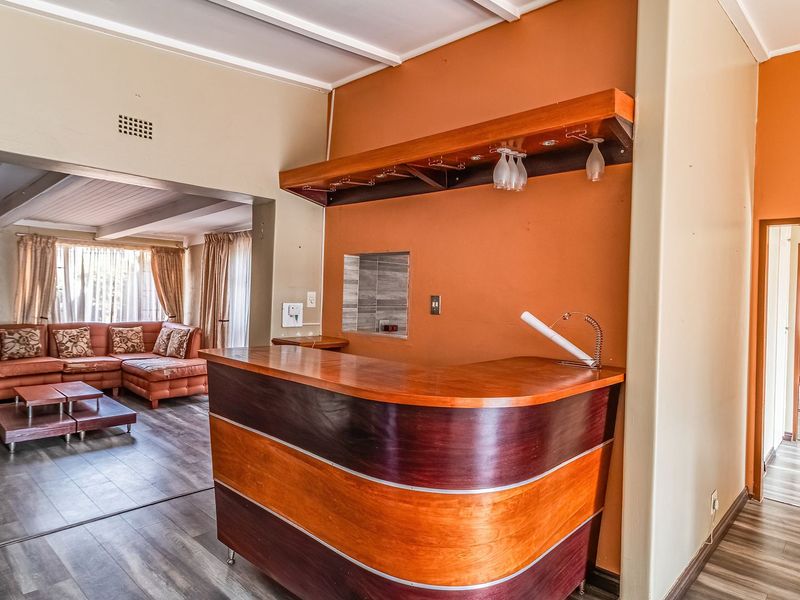 A dedicated bar area featuring a built-in wooden counter, overhead glass storage, and a recessed wall niche, adjacent to the main living space.