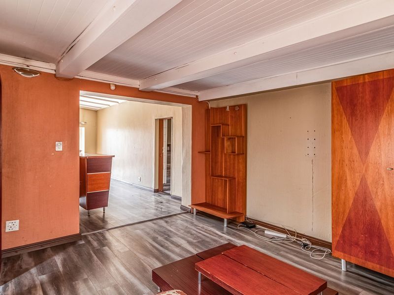 Living room featuring laminate flooring, exposed beam ceiling, and built-in cabinetry, offering a functional space with potential for cosmetic updates.
