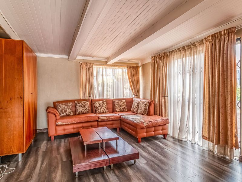 A living room featuring timber-look laminate flooring, a timber-clad ceiling, and a sliding glass door with security gate leading to the exterior.