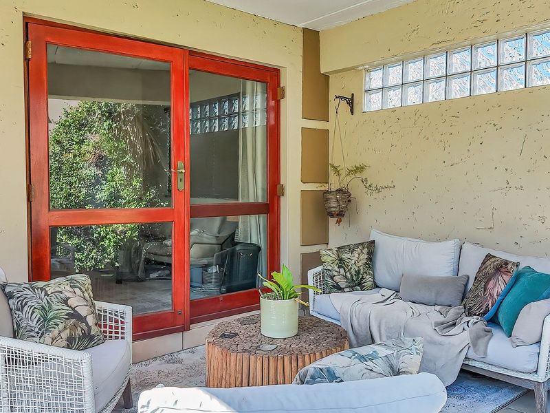 A covered patio area featuring textured walls, glass block clerestory windows, and double glass doors providing access to the interior living space.