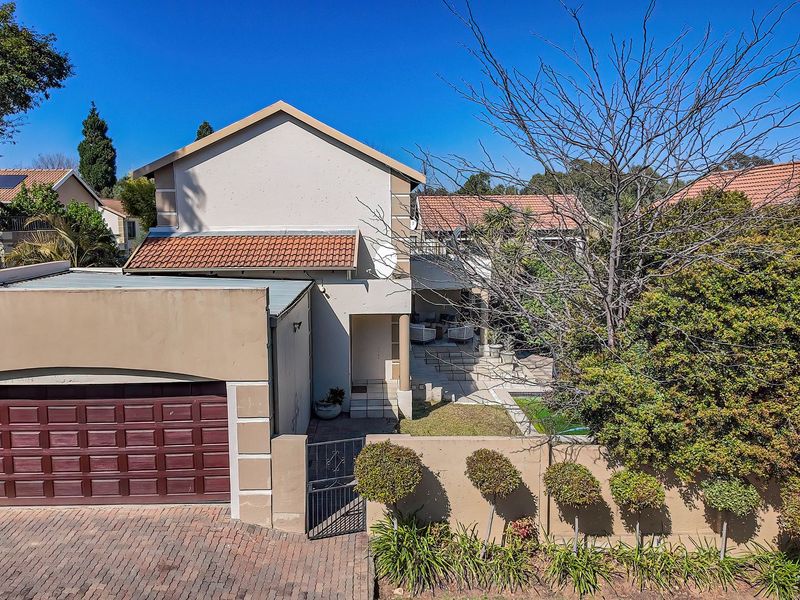 Front elevation of a townhouse featuring a paved driveway, single garage, and a private entrance with a small garden area.