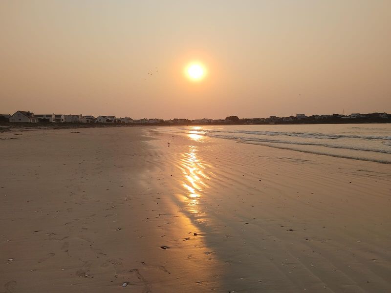 A scenic sunset view overlooking the coastline and beach, highlighting the property's desirable coastal location and natural surroundings.