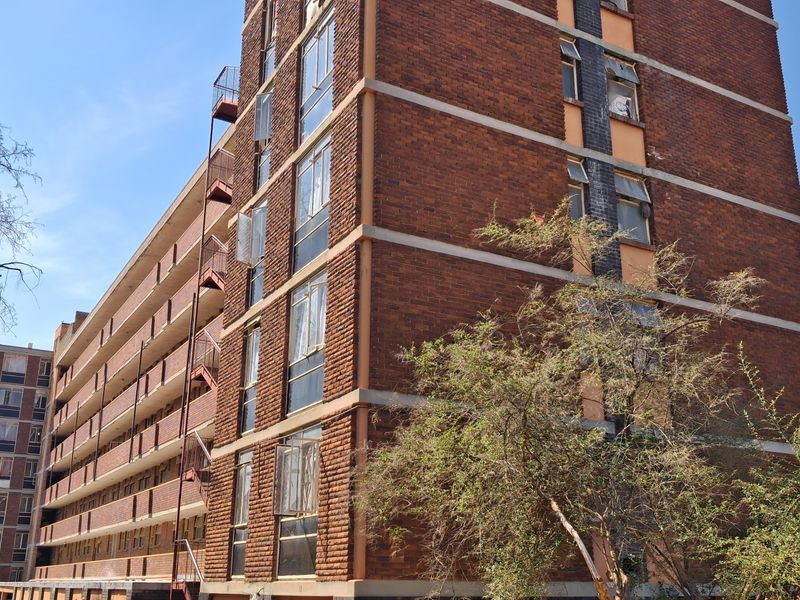 Exterior view of a multi-story apartment building featuring a classic brick facade and external fire escape staircases.
