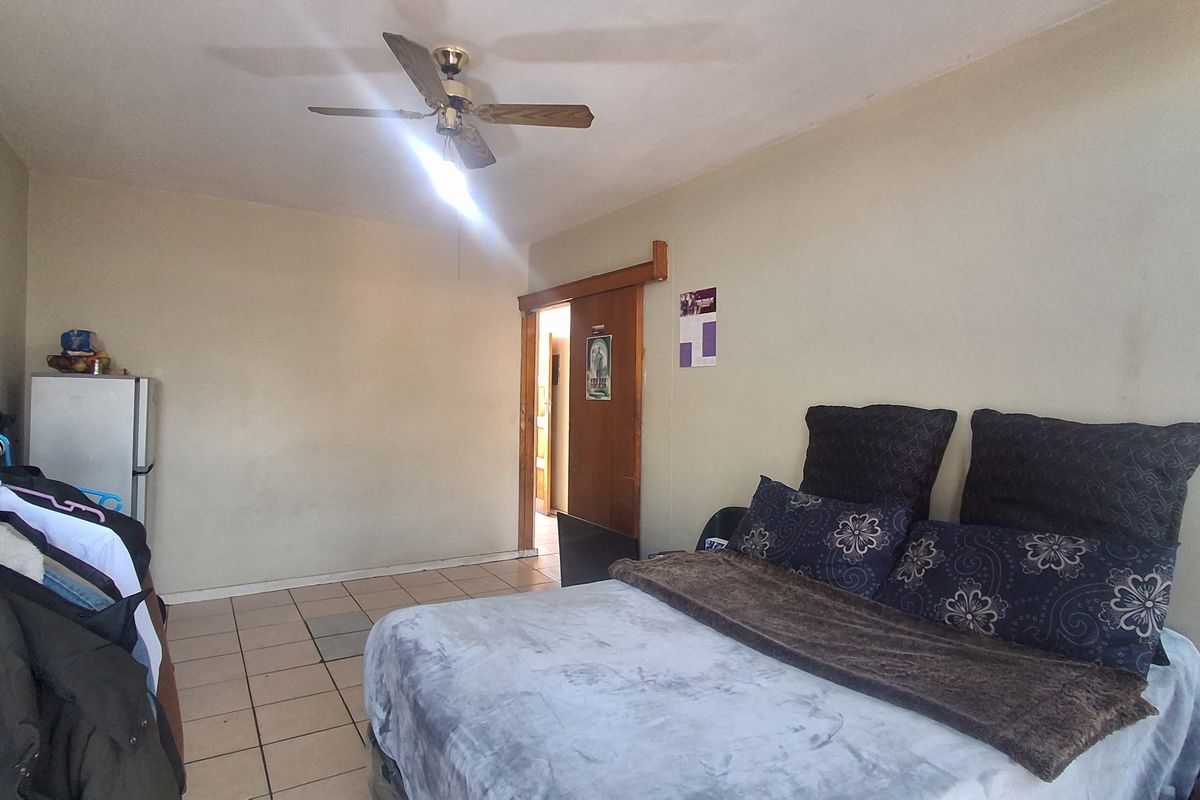 A bedroom featuring tiled flooring, a ceiling fan, and a sliding door entrance.