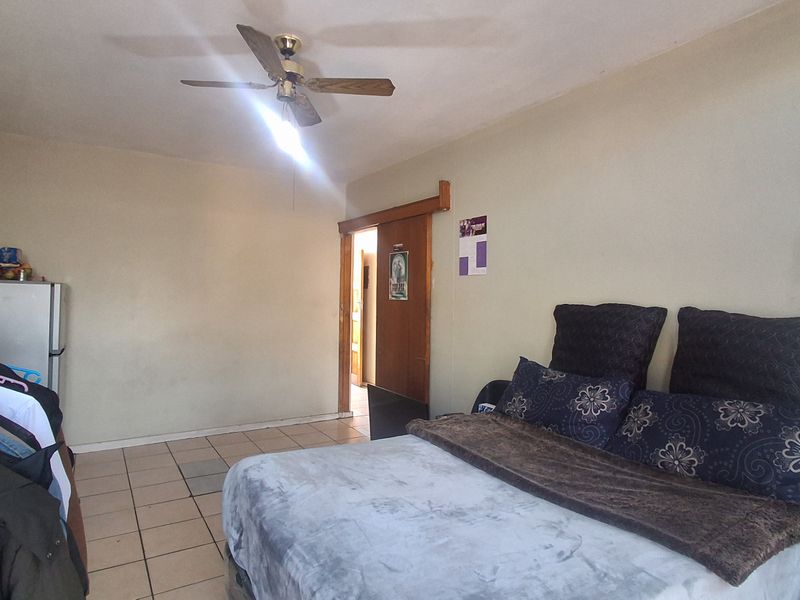 A bedroom featuring tiled flooring, a ceiling fan, and a sliding door entrance.