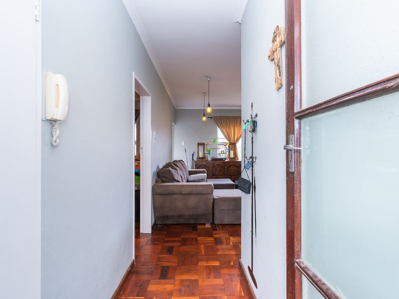 A functional hallway featuring classic parquet flooring and an integrated intercom system, providing a clear transition into the main living area.