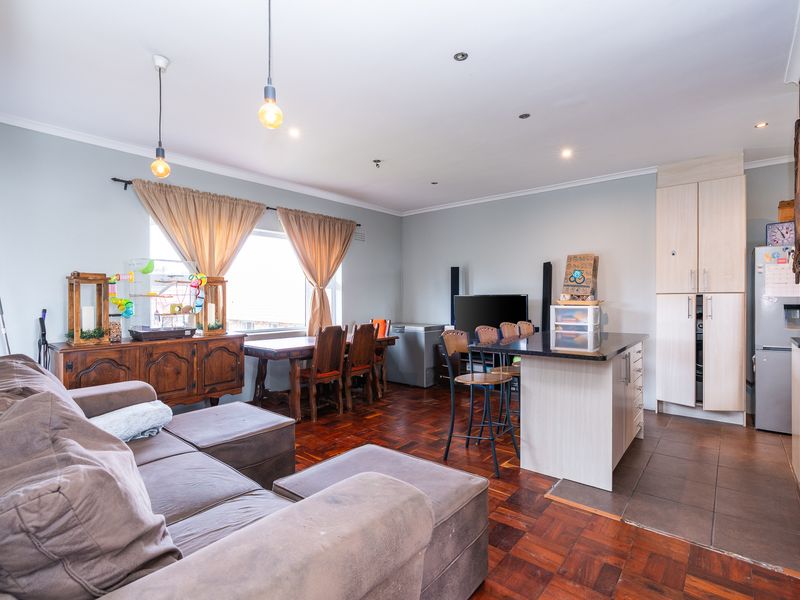 Open-plan living and kitchen area featuring parquet flooring, a central kitchen island with granite countertop, and ample built-in cabinetry.