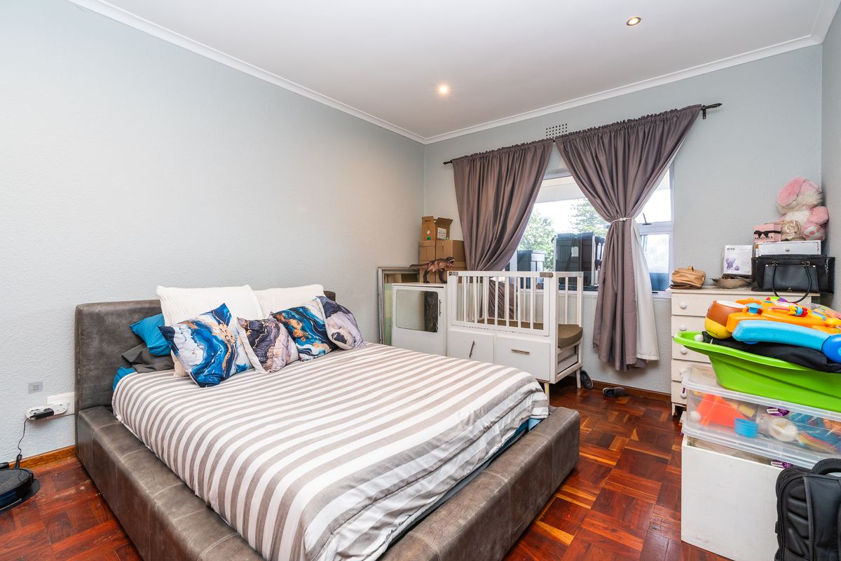 A bedroom featuring classic parquet flooring, recessed downlighting, and a window with curtain fixtures, offering a functional space with potential for modernization.