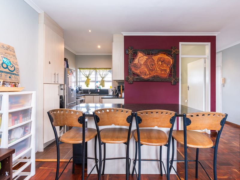 Open plan kitchen and dining area featuring a granite breakfast bar, built-in cabinetry, and traditional parquet flooring.