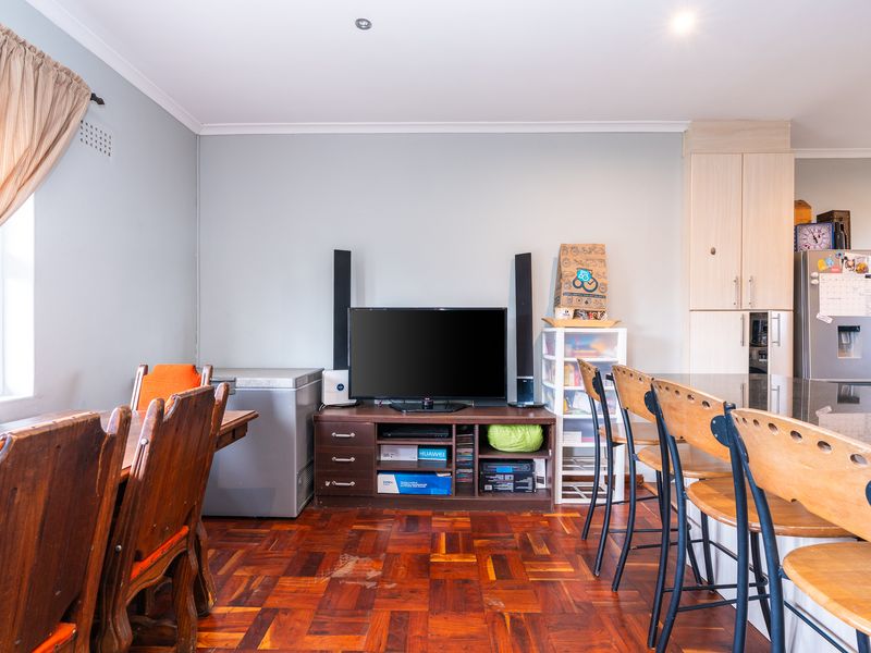 Open plan living and kitchen area featuring parquet flooring, built-in cabinetry, and a kitchen island with breakfast bar seating.