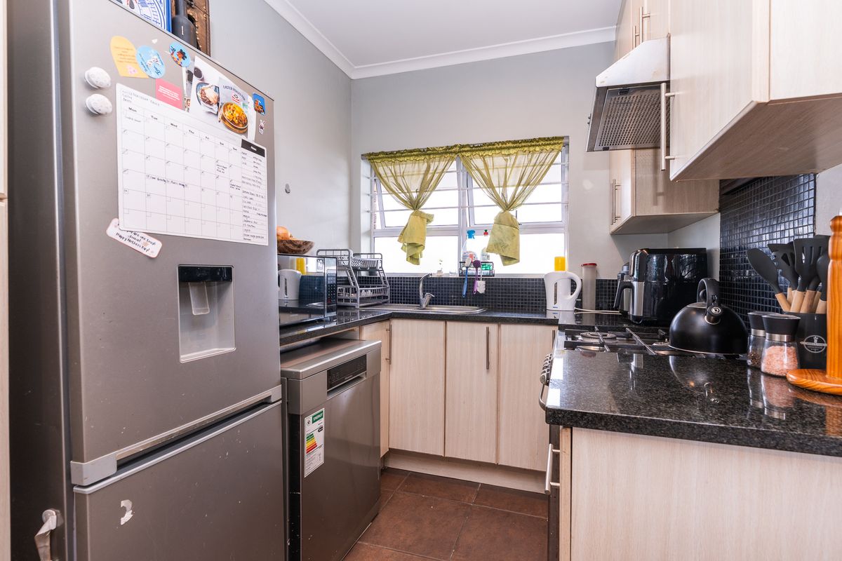 A functional kitchen featuring granite countertops, built-in cabinetry, a gas hob with extractor fan, and a tiled backsplash.
