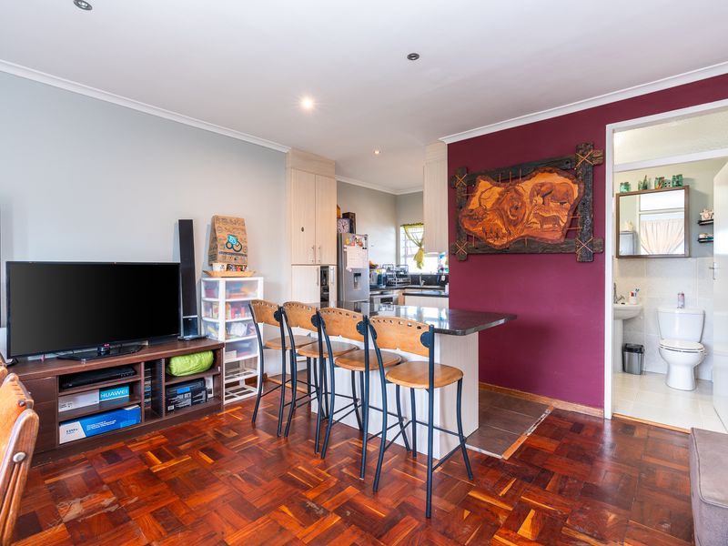 Open plan living area featuring parquet flooring, a breakfast bar, and direct access to an adjacent bathroom.