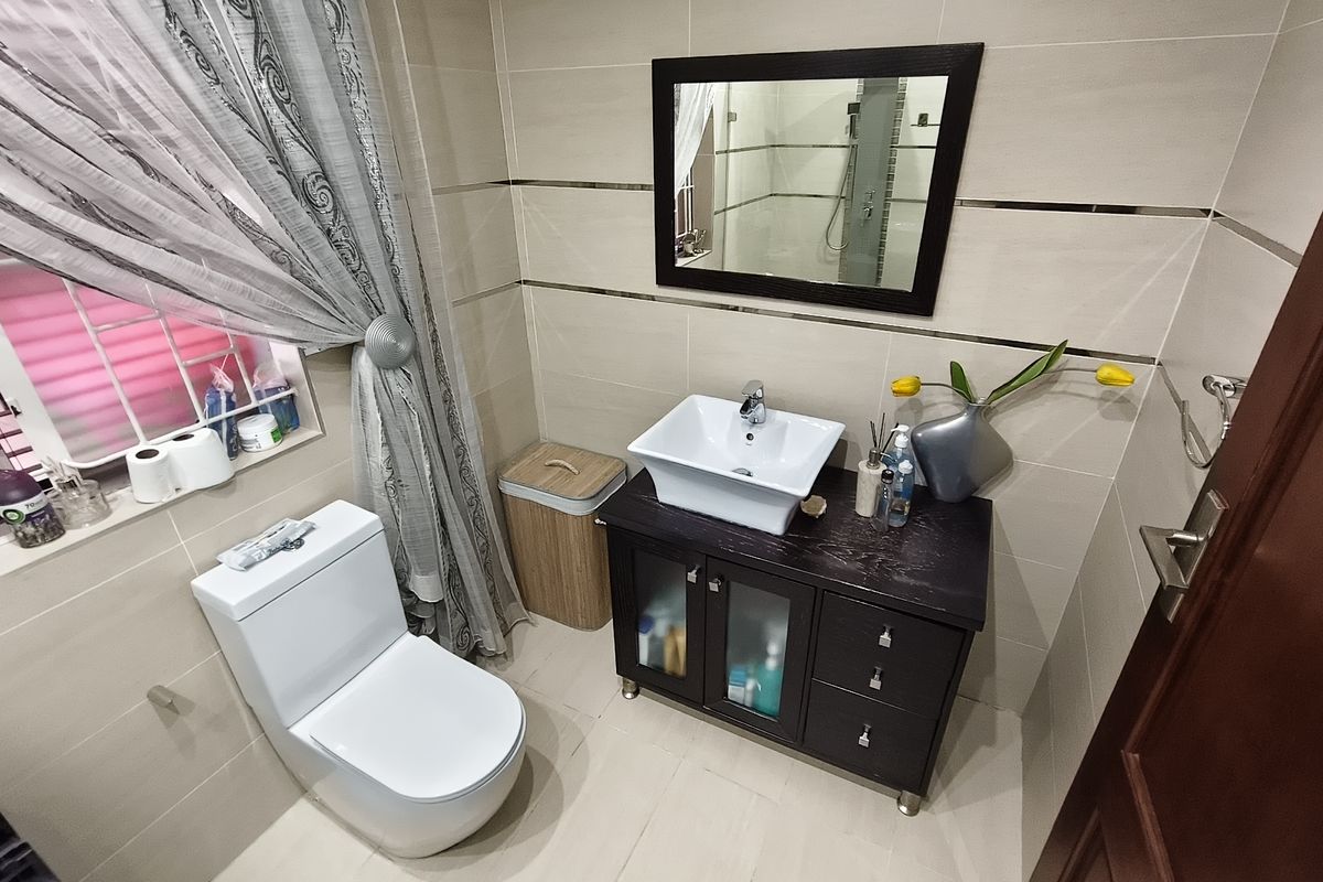 A well-maintained bathroom featuring a modern vessel sink on a dark vanity cabinet, tiled walls with decorative accents, and a ceramic toilet.