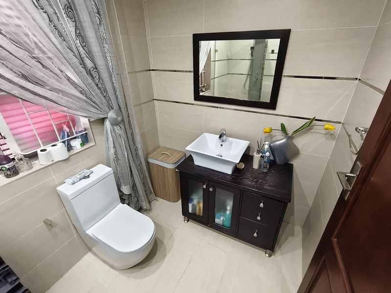 A well-maintained bathroom featuring a modern vessel sink on a dark vanity cabinet, tiled walls with decorative accents, and a ceramic toilet.