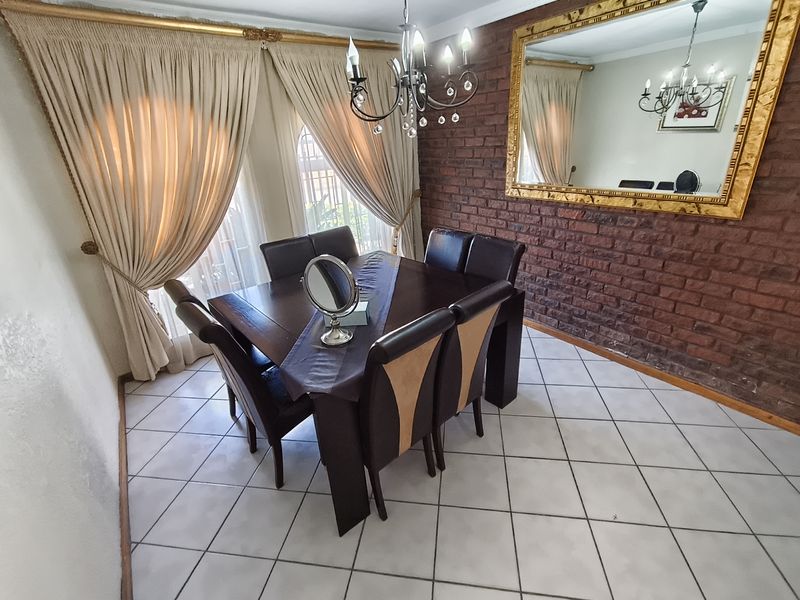 A dining room featuring an exposed brick feature wall, ceramic tile flooring, and a decorative chandelier, providing a classic and defined dining space.