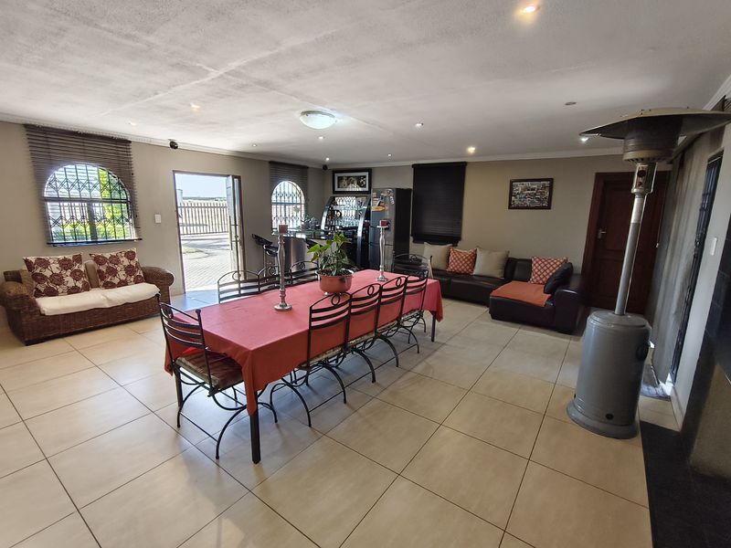 Spacious open-plan living and dining area featuring tiled floors, recessed lighting, and a built-in bar with direct access to the exterior.