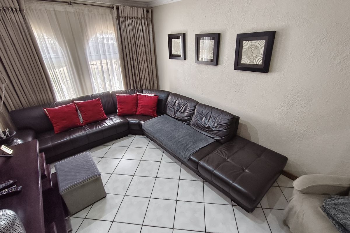 A comfortable living room featuring tiled flooring, recessed ceiling lighting, and arched windows with floor-to-ceiling curtains.