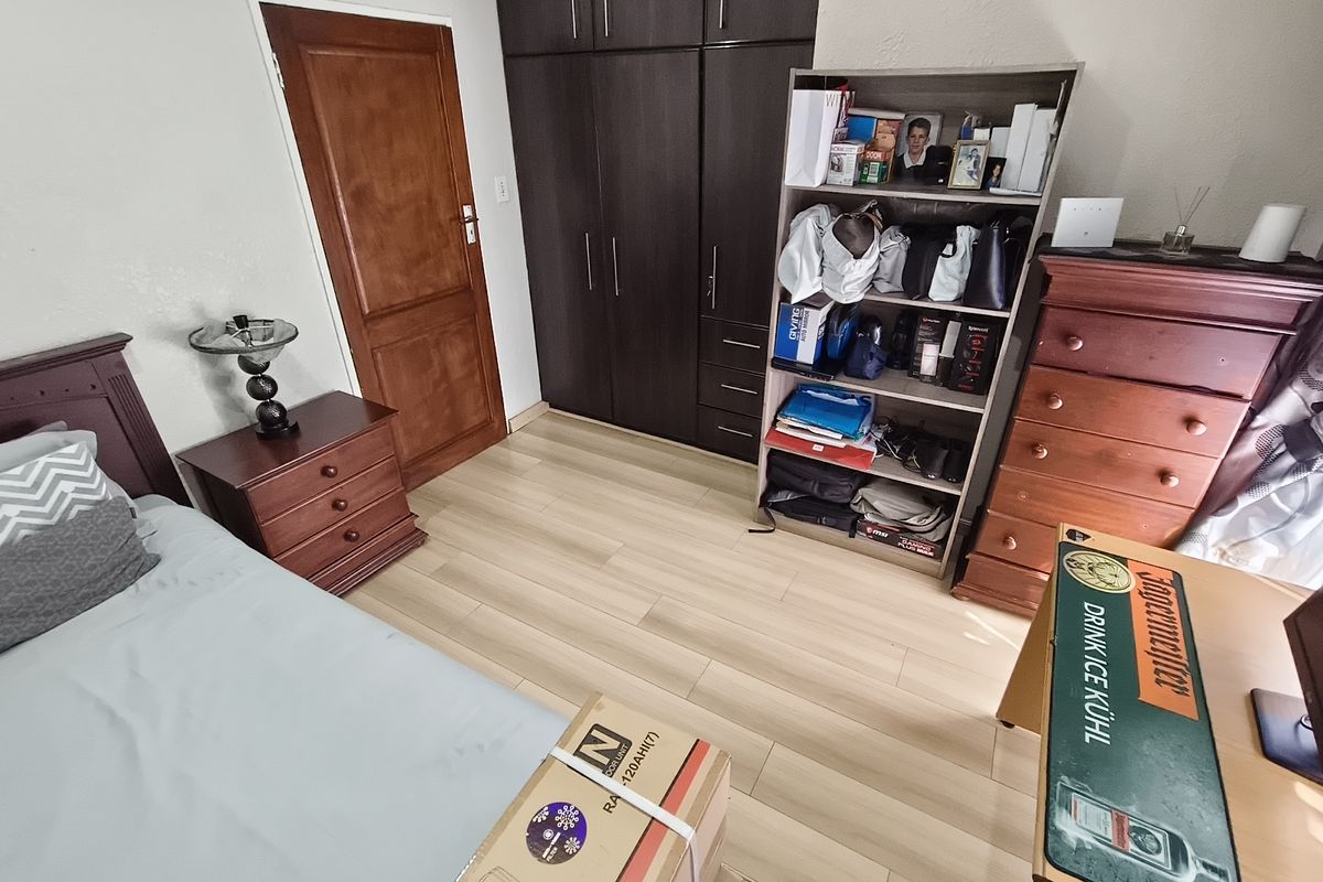 A bedroom featuring laminate flooring and dark wood built-in cupboards, providing functional storage space.