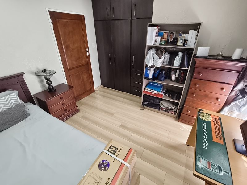 A bedroom featuring laminate flooring and dark wood built-in cupboards, providing functional storage space.