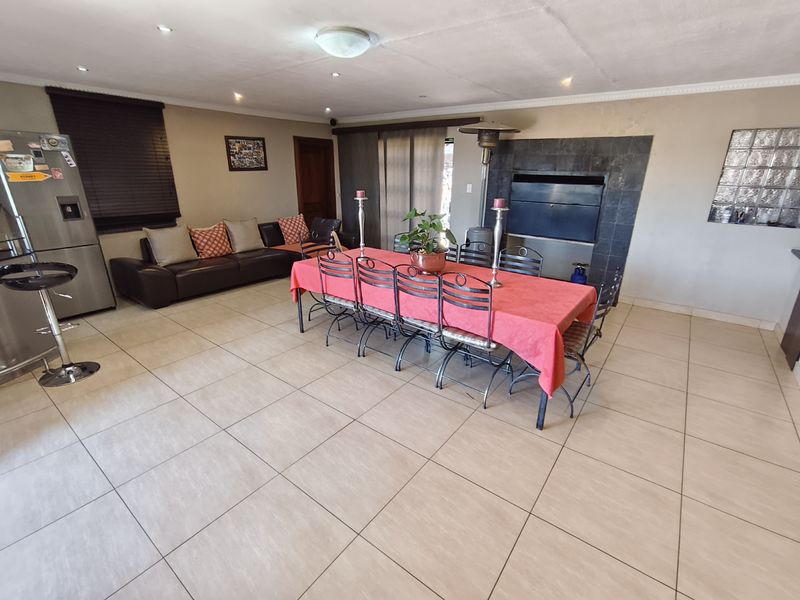 Spacious open-plan living and dining area featuring tiled floors, a built-in fireplace, and recessed lighting, offering a versatile layout for family living.