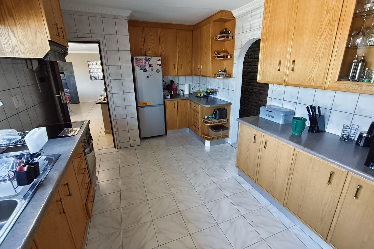A functional kitchen featuring traditional wooden cabinetry, tiled flooring, and a tiled backsplash, offering a classic layout with ample storage and workspace.