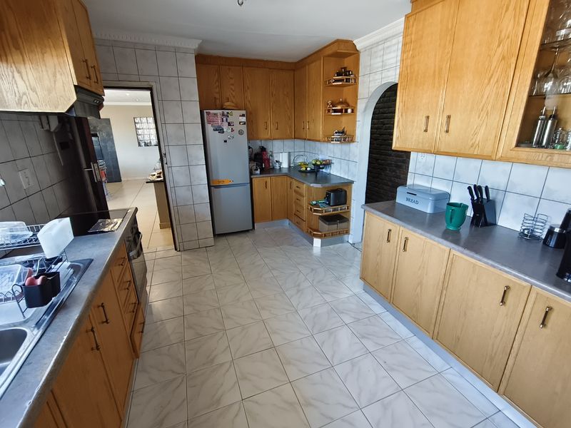 A functional kitchen featuring traditional wooden cabinetry, tiled flooring, and a tiled backsplash, offering a classic layout with ample storage and workspace.