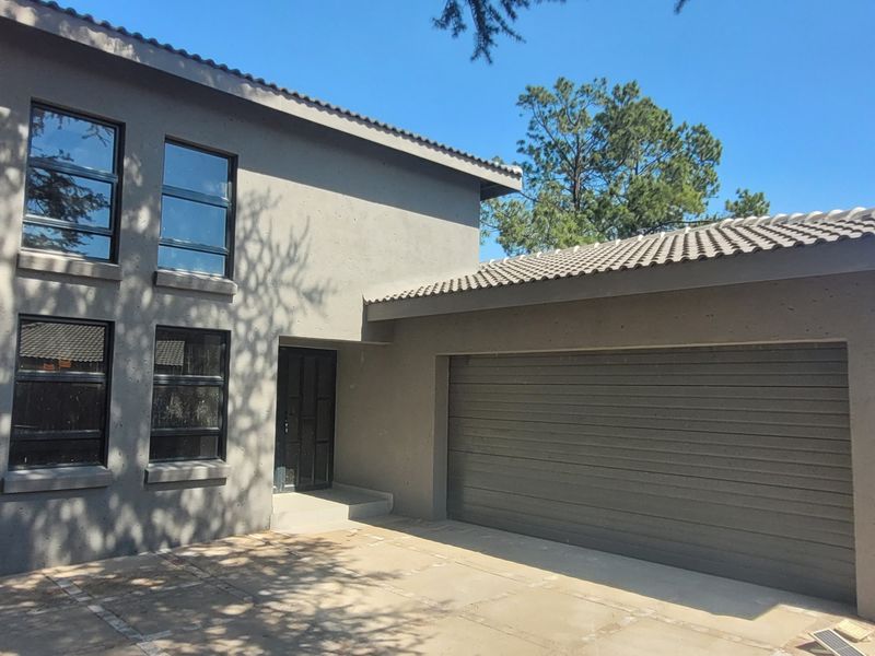 Front elevation of a modern double-story house featuring a concrete driveway, integrated garage, and dark-framed windows.