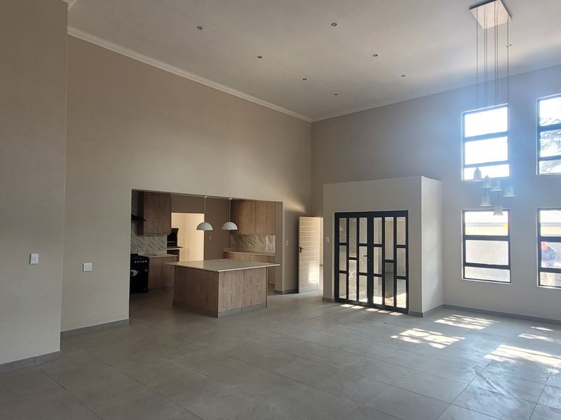 Spacious open-plan living area featuring high ceilings, large windows for natural light, and a modern kitchen with a central island and built-in cabinetry.
