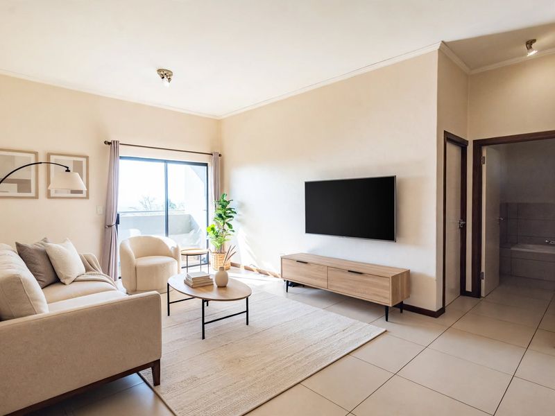 A bright and well-maintained living room featuring neutral tiled flooring, coving, and a sliding glass door providing access to an outdoor area.