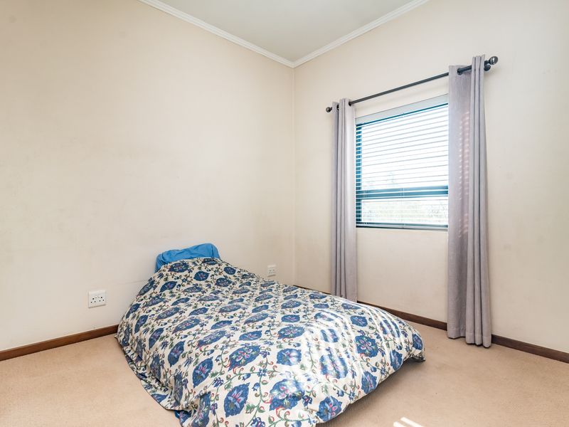 A standard bedroom featuring carpeted flooring, a window with fitted blinds, and neutral wall finishes.