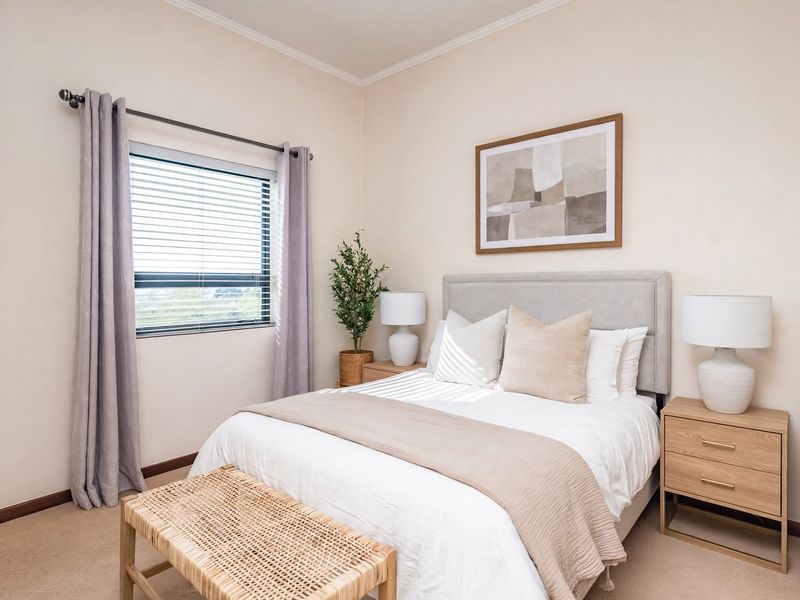 A well-maintained bedroom featuring neutral wall tones, carpeted flooring, and a window with fitted blinds, offering a comfortable and inviting living space.
