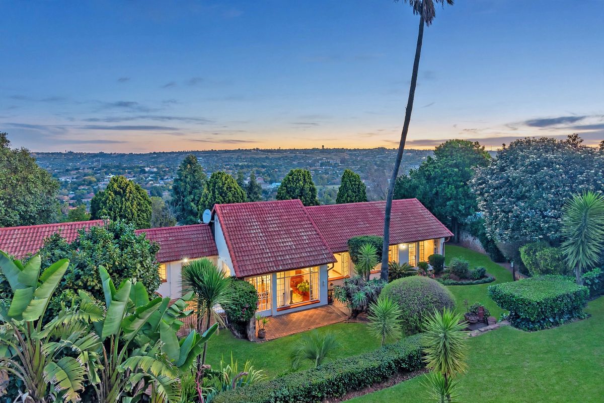 Aerial view of the property featuring a terracotta tiled roof, paved patio area, and expansive landscaped garden overlooking the surrounding neighborhood.