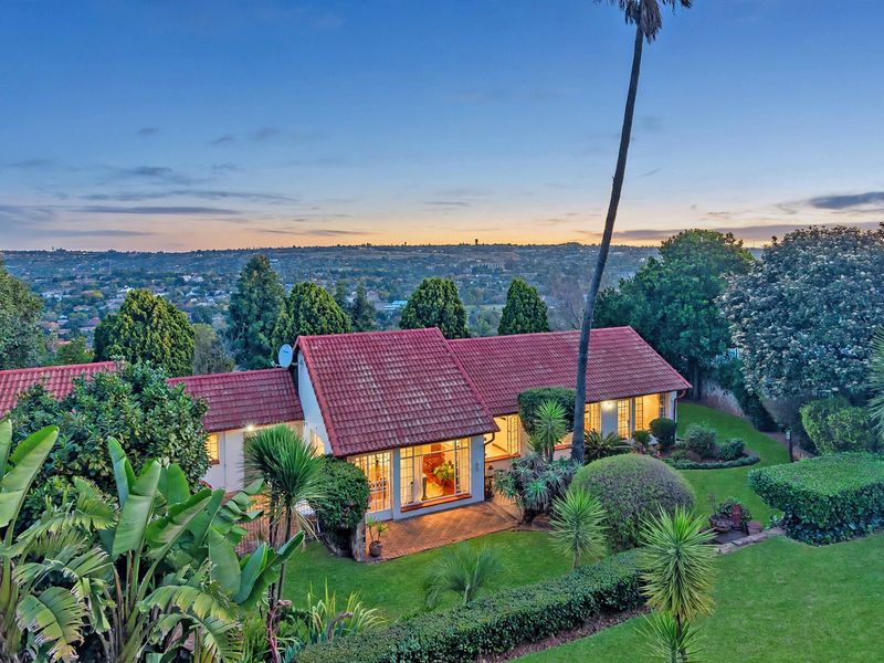 Aerial view of the property featuring a terracotta tiled roof, paved patio area, and expansive landscaped garden overlooking the surrounding neighborhood.