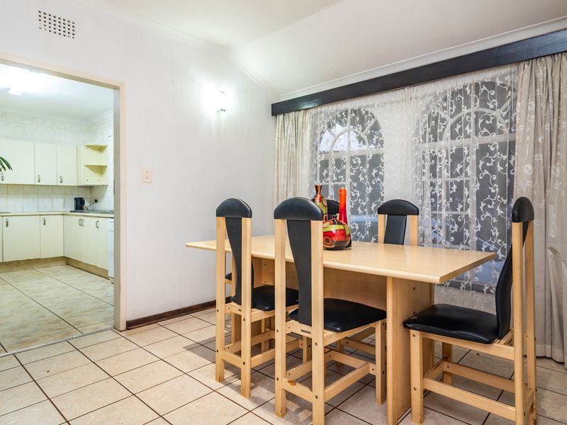 Dining area featuring tiled flooring and arched windows, with an open transition into the adjacent kitchen space.