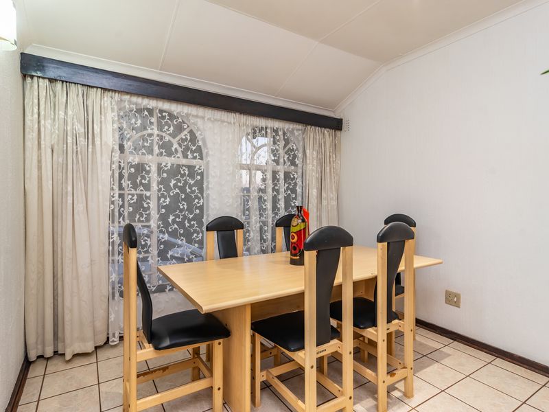 A dining room featuring tiled flooring, a vaulted ceiling, and arched windows that provide natural light.