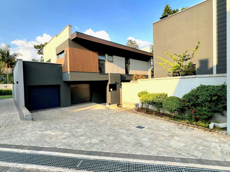 Modern double-story residential property featuring a contemporary facade, timber accents, and a spacious paved driveway leading to a double garage.
