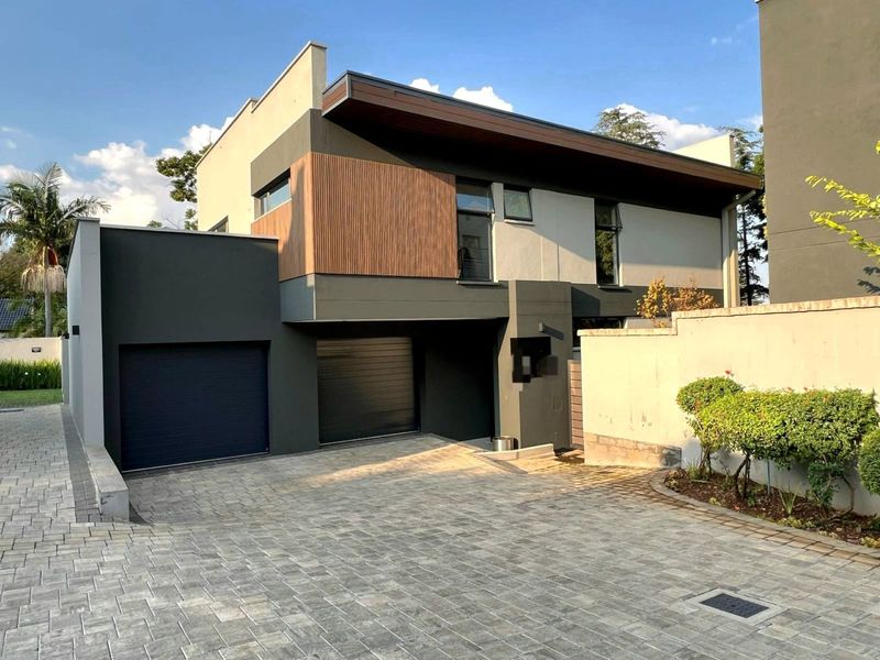 Modern double-storey residential property featuring a contemporary facade with timber accents, a paved driveway, and a double garage.