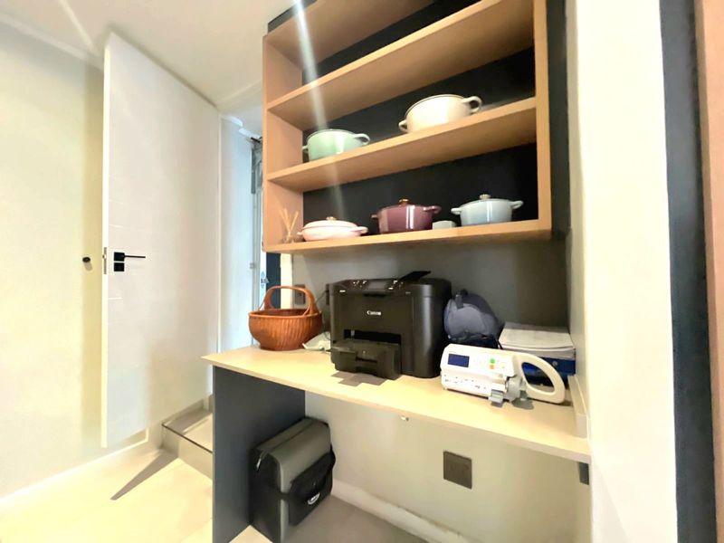A functional utility space featuring built-in shelving and a desk area, providing convenient storage and workspace.