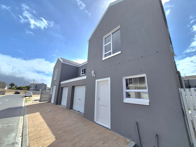 Front elevation of a modern double-storey house featuring a paved driveway, two roller garage doors, and a neutral grey exterior finish.