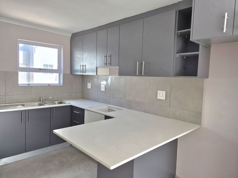 Modern kitchen featuring grey built-in cabinetry, stone countertops, a double basin sink, and a functional breakfast nook area.