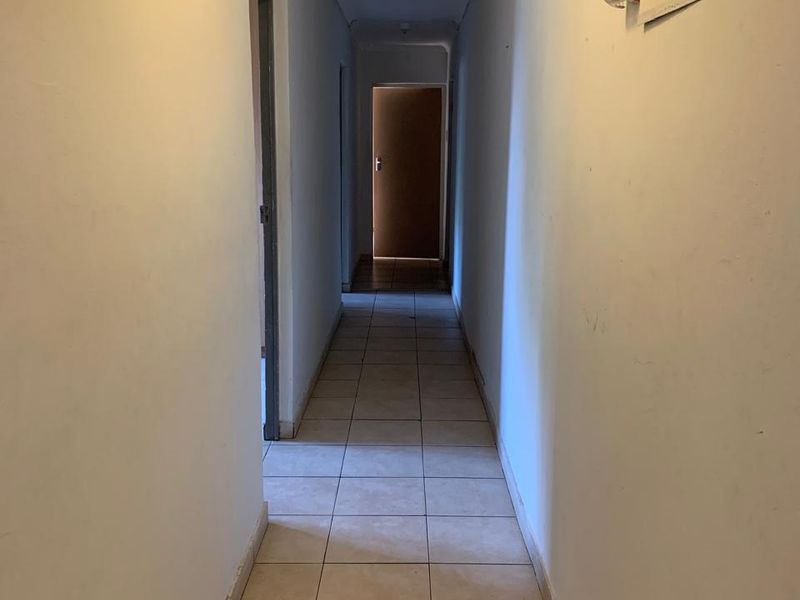 A narrow interior hallway featuring tiled flooring and a wall-mounted electrical distribution board, showing signs of wear on the walls.