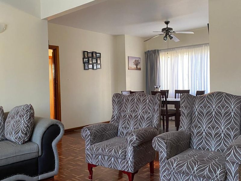 Open plan living and dining area featuring classic parquet flooring and a ceiling fan, offering a spacious layout with natural light.