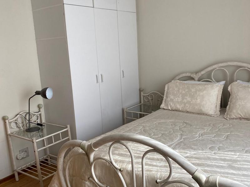 A bedroom featuring a built-in white wardrobe and laminate flooring, providing functional storage space.