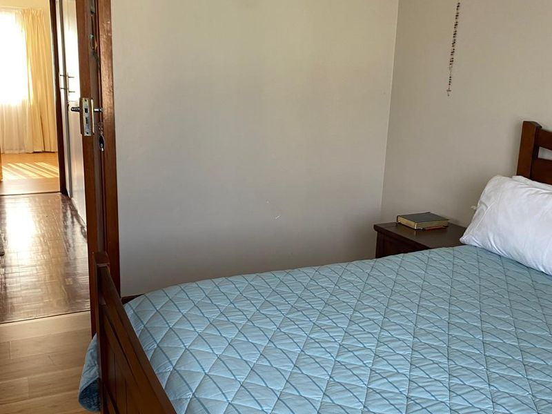 A bedroom featuring laminate flooring and a timber door frame, with a view into the adjacent hallway.