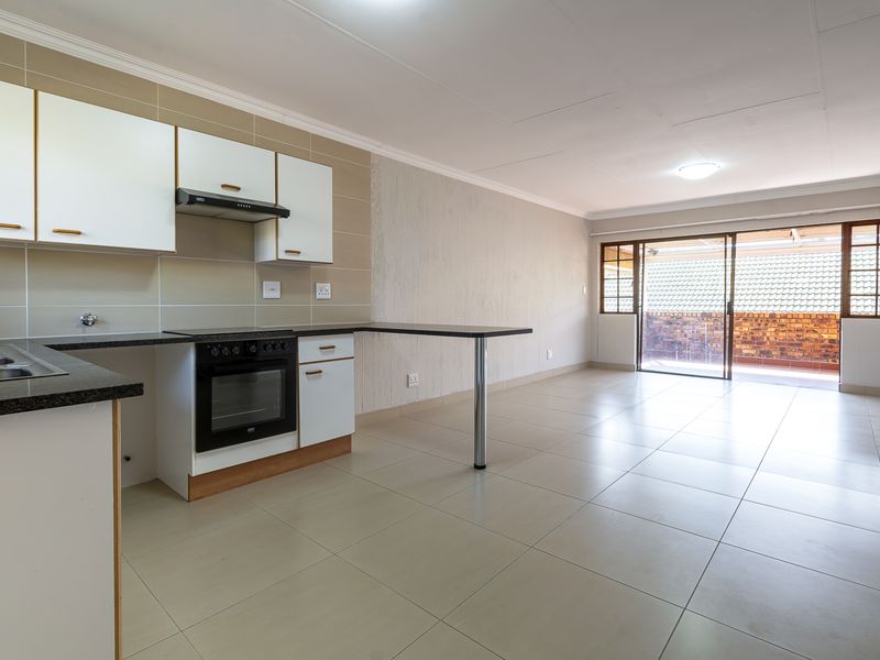 Spacious open-plan kitchen and living area featuring tiled floors, built-in cabinetry with granite countertops, and sliding doors leading to an outdoor space.